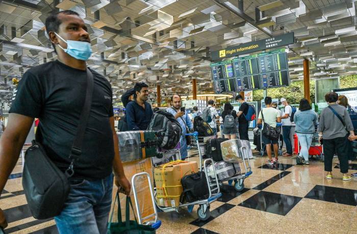 Călătorii stau la coadă pentru a se înregistra pentru plecarea zborului lor pe aeroportul Changi din Singapore