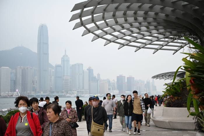 Turiștii din China continentală se plimbă de-a lungul frontului portului din Hong Kong