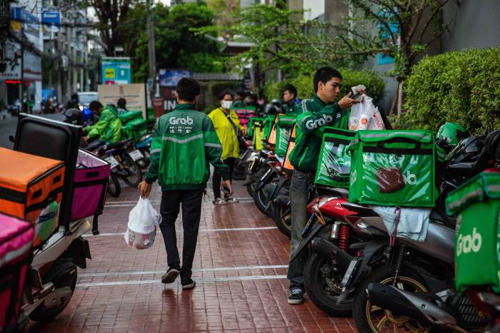 Șoferii care livrează mâncare pe motocicletă ridică mâncare la mall-ul Major Ekamai din Bangkok, Thailanda