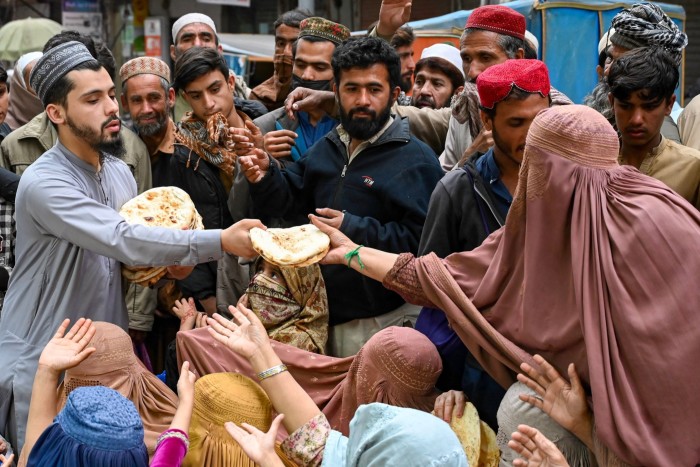 Femeile așteaptă pâine gratuită la un punct de distribuție din Peshawar, Pakistan