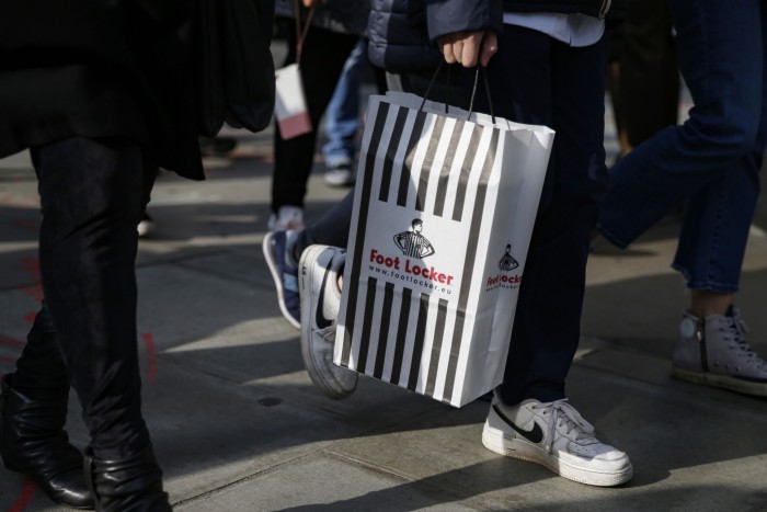 Un cumpărător poartă o pungă de cumpărături Foot Locker în Londra, Marea Britanie