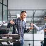 young handsome man choosing car car showroom