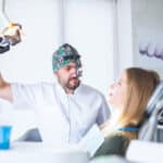 dentist wearing dental loupe binoculars treating female patient