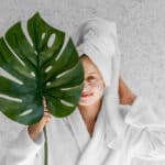 front view woman holding monstera leaf